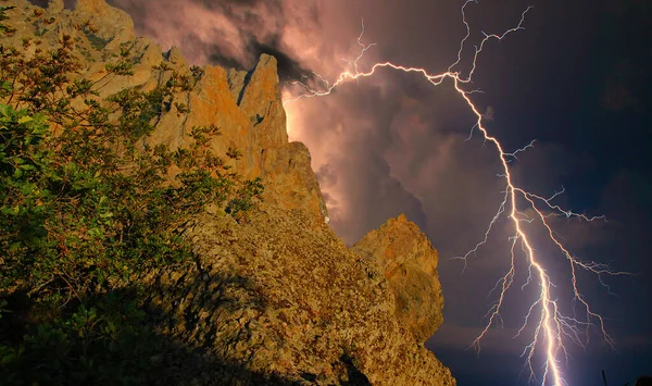 Karadağ 'ın kayalarının üzerinde şimşek çakıyor. Karadeniz kıyısı, Doğu Kırım, dağlarda çarpıcı bir fırtına manzarası, yıldırımlar ve parıltılarla