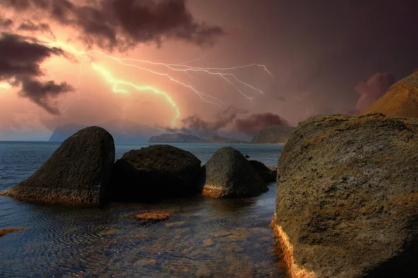 Karadağ 'ın kayalarının üzerinde şimşek çakıyor. Karadeniz kıyısı, Doğu Kırım, dağlarda çarpıcı bir fırtına manzarası, yıldırımlar ve parıltılarla