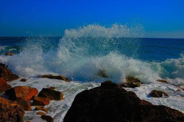 Karadeniz 'in komik dalgaları ve sıçramaları, Kırım. Dalgalar, Feodosia ve Koktebel yakınlarındaki Karadeniz, Doğu Kırım 'ın sığ sularında kıyı kayalıklarında kırdıyor. Sprey yukarı uçar. Sakin bir yaz günü 