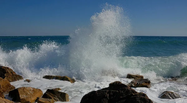 Karadeniz 'in komik dalgaları ve sıçramaları, Kırım. Dalgalar, Feodosia ve Koktebel yakınlarındaki Karadeniz, Doğu Kırım 'ın sığ sularında kıyı kayalıklarında kırdıyor. Sprey yukarı uçar. Sakin bir yaz günü 