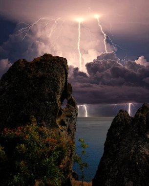 Karadeniz kıyısında şimşekler çakıyor, Kırım. Feodosiya ve Koktebel yakınlarındaki Karadeniz, Doğu Kırım 'ın sığ sularında, su ve kıyı kayaları üzerinde şimşekler çakıyor.
