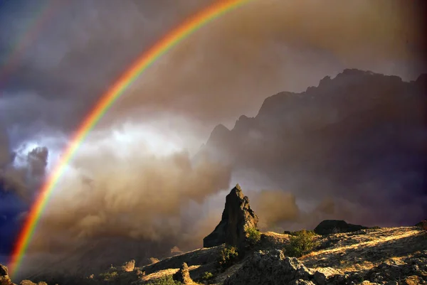 Dağlarda gökkuşağı, Kırım Karadağ dağ sırasının kayalarının üzerinde bir gökkuşağı parlıyor. Kayalık kayalıklar, cansız ve terk edilmiş. Volkanik kökenli kayalar. Gök gürültülü fırtınadan sonra çekildi