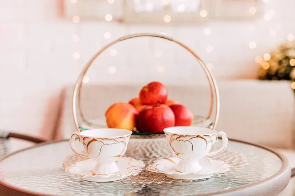 瓷杯站在一个盛有红苹果的玻璃器皿旁边 — 图库照片