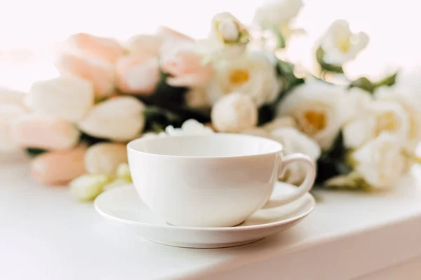 Белая Чашка Блюдце Стоит Фоне Белых Тюльпанов — стоковое фото