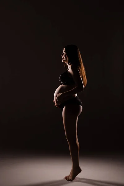 Femme enceinte en lingerie étreint son ventre avec ses mains — Photo