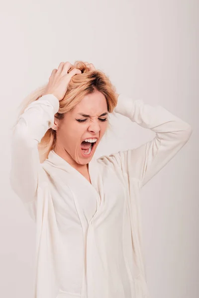 A girl in a white shirt holds on to her head and screams. — Stock Photo, Image