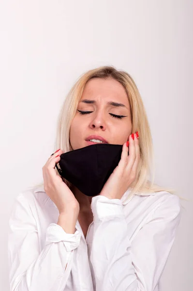 A very sad girl closes her eyes and puts a coronavirus mask on her face — Stock Photo, Image