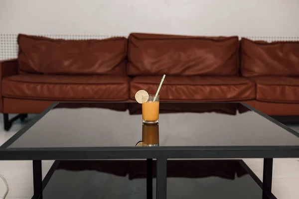 Un bicchiere di succo d'arancia si trova su un tavolo nero di vetro — Foto Stock