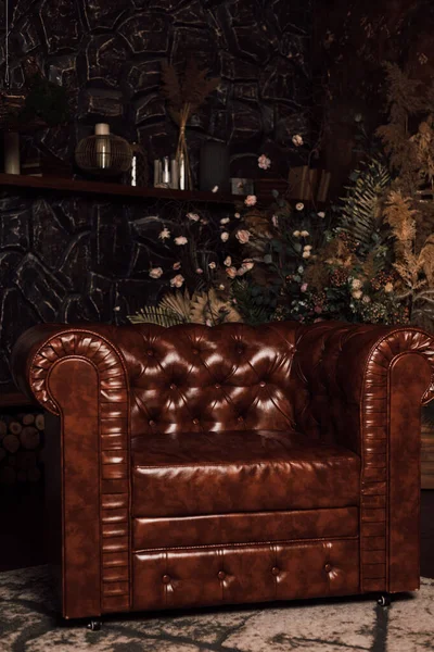 Koyu renkli tuğla bir duvara yaslanmış kahverengi deri koltuk.