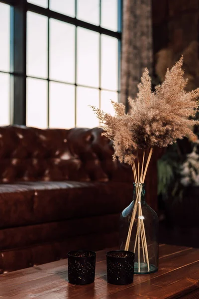 Vaso con fiori secchi si erge su un tavolo di legno all'interno — Foto Stock