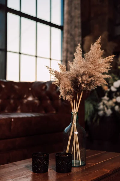 Vaas met gedroogde bloemen staat op een houten tafel in het interieur — Stockfoto