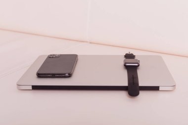 Telefon ve saat dizüstü bilgisayarın üstünde.