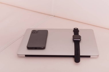 Telefon ve saat dizüstü bilgisayarın üstünde.