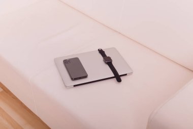 Telefon ve saat dizüstü bilgisayarın üstünde.