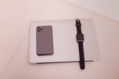 Telefon ve saat dizüstü bilgisayarın üstünde.