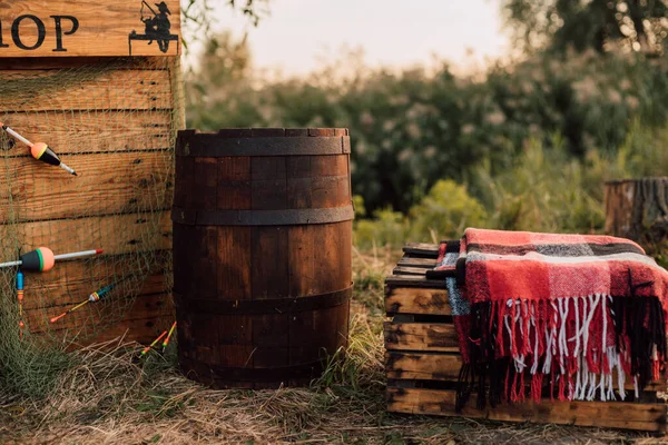 En el pueblo en la naturaleza en la hierba hay un barril de madera y cajas de madera — Foto de Stock