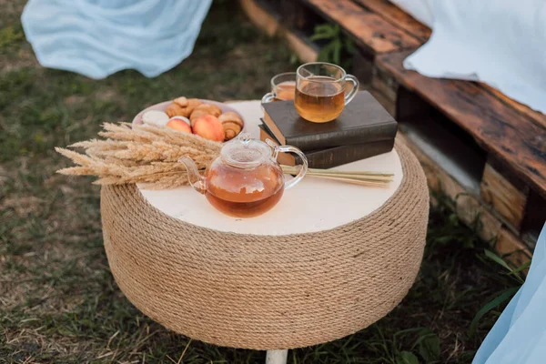 En la mesa de madera hay tazas de té, una tetera, un libro y flores secas — Foto de Stock