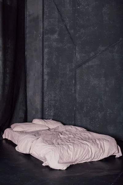 Beyaz yataklı yatak pencerenin yanındaki karanlık bir odada duruyor.