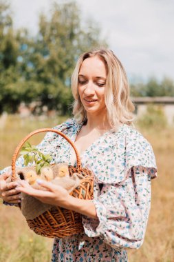 Genç bir kadın bir sepet ördek yavrusu tutuyor ve gülümsüyor.