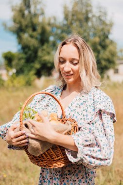 Genç bir kadın bir sepet ördek yavrusu tutuyor ve gülümsüyor.