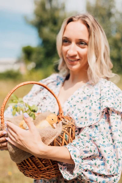 Genç ve güzel bir kız elinde ördek yavrusuyla bir sepet tutuyor.