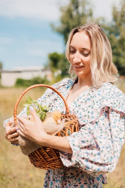 Genç ve güzel bir kız elinde ördek yavrusuyla bir sepet tutuyor.