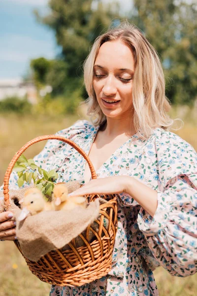 Genç ve güzel bir kız elinde ördek yavrusuyla bir sepet tutuyor.
