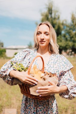 Kırsal kesimde genç bir kız elinde ördek yavrusu dolu bir sepet tutuyor.