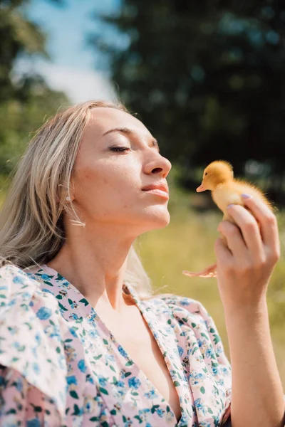 Eine junge Frau hält ein Entlein in ihren Händen und schließt genüsslich die Augen — Stockfoto