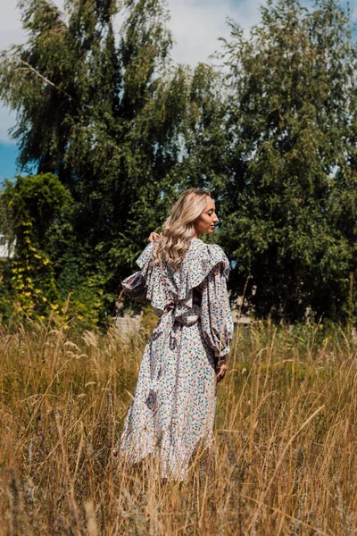 Een jong meisje in een lange jurk loopt in het veld — Stockfoto