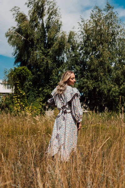 A young girl in a long dress walks in the field — Photo