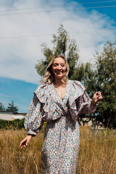 A young girl in a long dress walks in the field — 스톡 사진