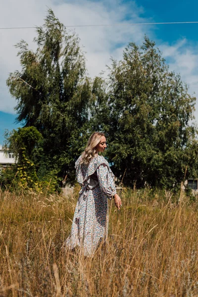 Une jeune fille en robe longue se promène dans les champs — Photo