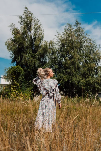 A young girl in a long dress walks in the field — Photo