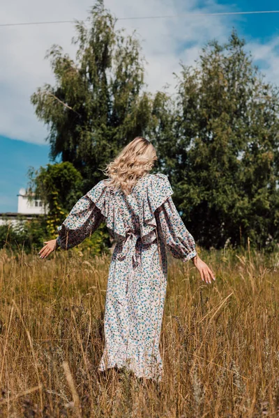 Une jeune fille en robe longue se promène dans les champs — Photo