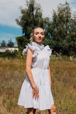 Kırsal elbiseli güzel bir sarışın tarlada yürüyor.