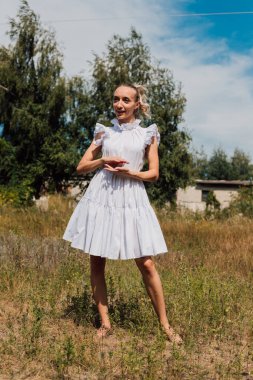 Kırsal elbiseli güzel bir sarışın tarlada yürüyor.