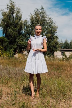 Kırsal elbiseli güzel bir sarışın tarlada yürüyor.