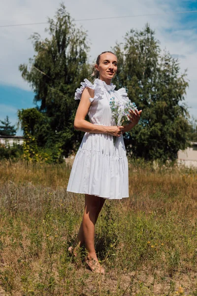 Kırsal elbiseli genç bir kız elinde çiçekleri tutuyor.