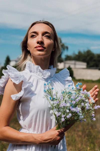 Een jong mooi meisje houdt bloemen in haar handen — Stockfoto