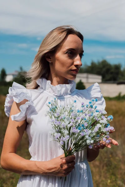 A young beautiful girl holds flowers in her hands — Photo