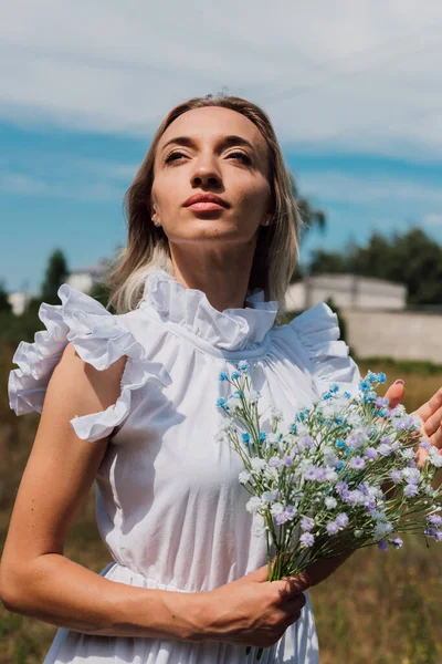 Genç ve güzel bir kız elinde çiçekler tutuyor.