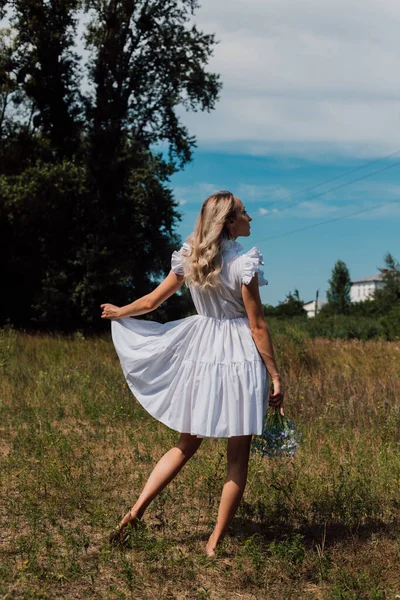 Kırsal elbiseli bir kız arkasını döndü ve elinde çiçekler tuttu.