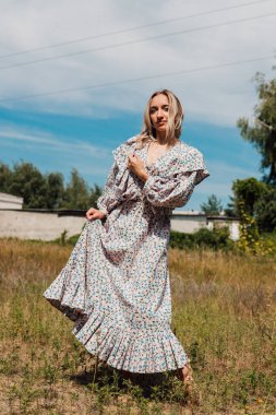 Uzun bir kırsalda çıplak ayakla dans eden genç bir kadın.