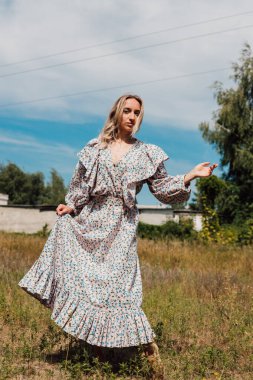 Uzun bir kırsalda çıplak ayakla dans eden genç bir kadın.