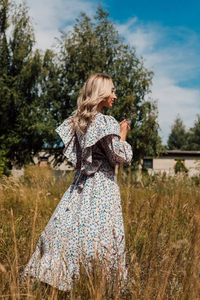 Une jeune femme en robe rustique se tient avec le dos et regarde au loin — Photo