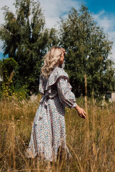Une jeune femme en robe rustique se tient avec le dos et regarde au loin — Photo