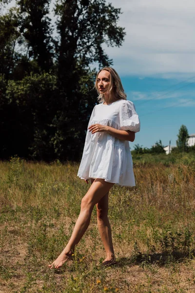 A young woman stands barefoot in a field and stares into the distance —  Fotos de Stock