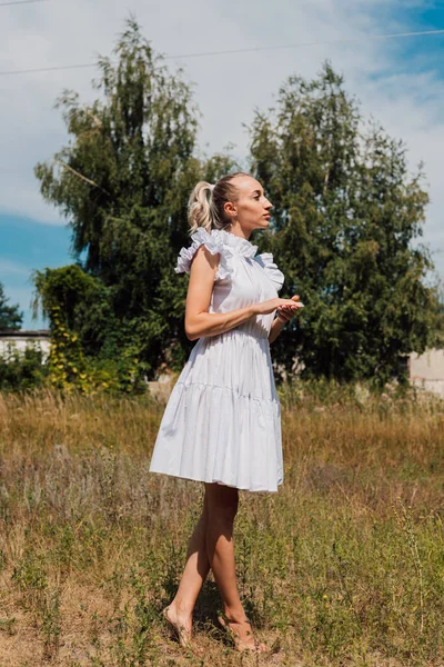 Une jeune femme se tient dans un champ et regarde au loin — Photo