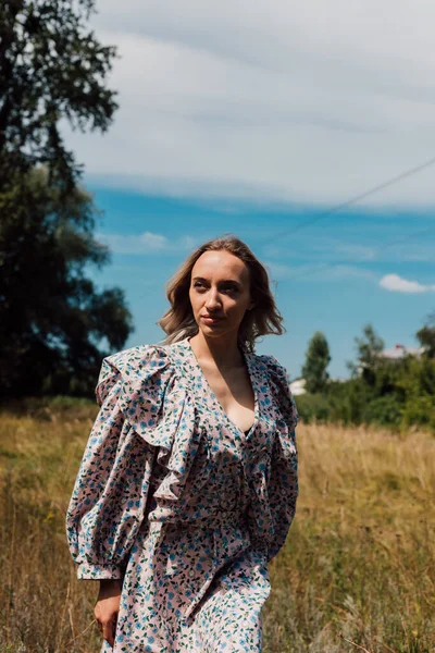  Kırsal bir elbise giymiş genç bir kadın köydeki bir tarlada rahatça yürüyor.